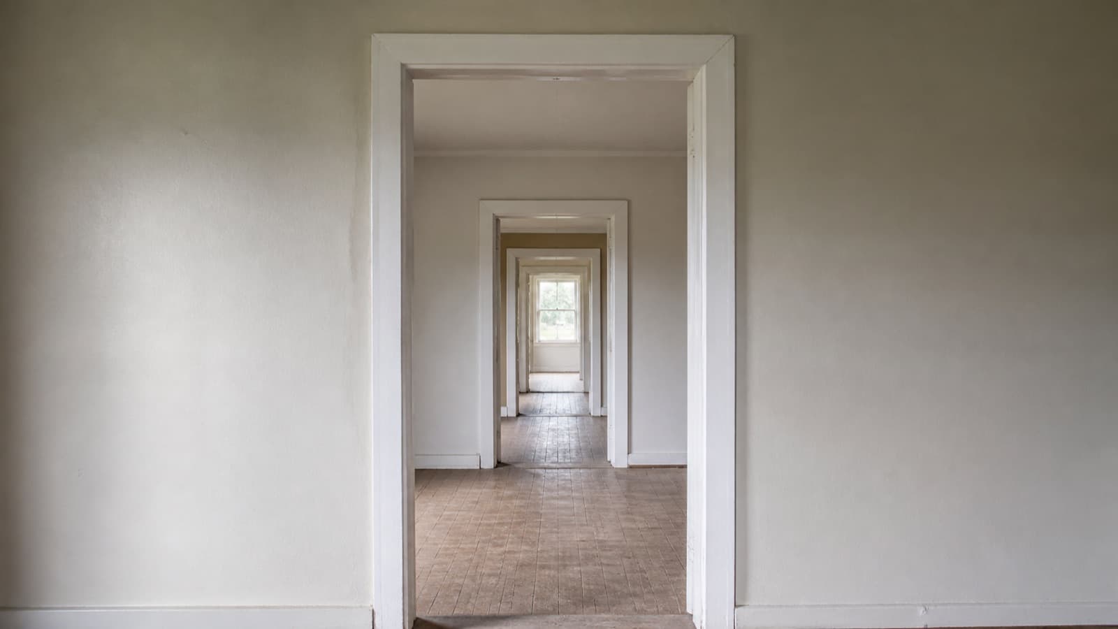A view straight through a series of aligned doorways receding through empty rooms.