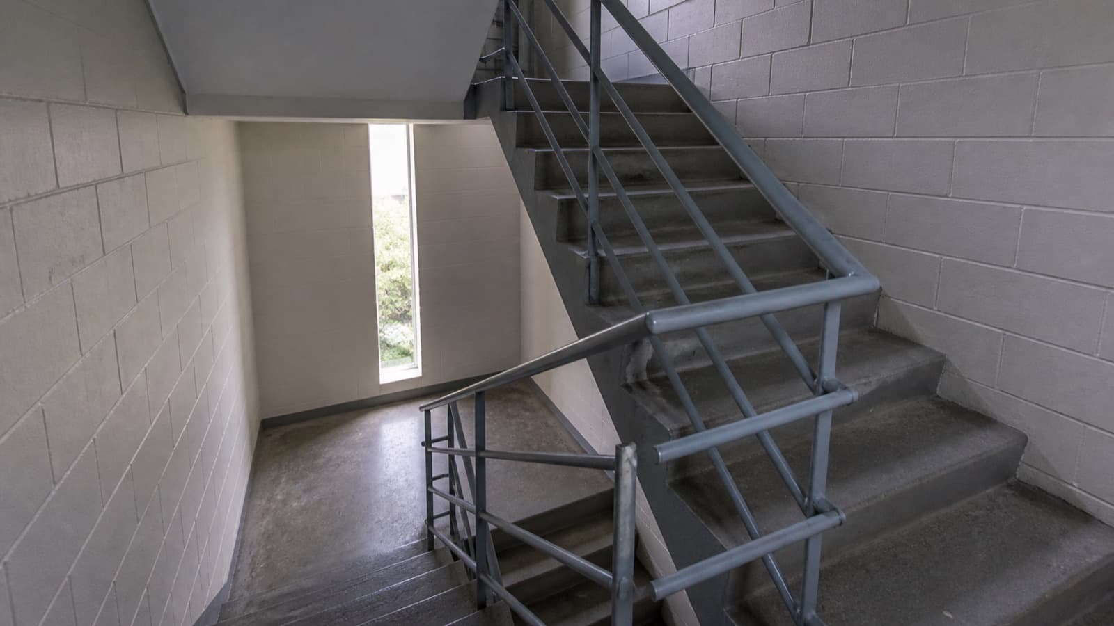 A plain concrete stairwell in a residential block, seen from a half-landing.